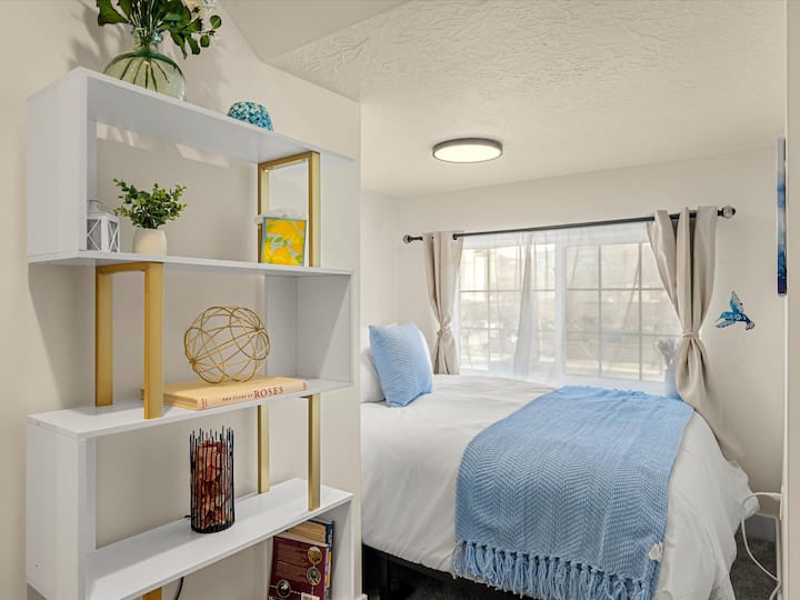 Bright, cozy bedroom, big window, and chic shelving.