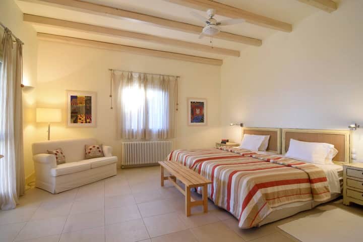 Голяма спалня с 2 двойни единични легла и единичен диван, който се отваря на веранда с чудесна гледка към морето