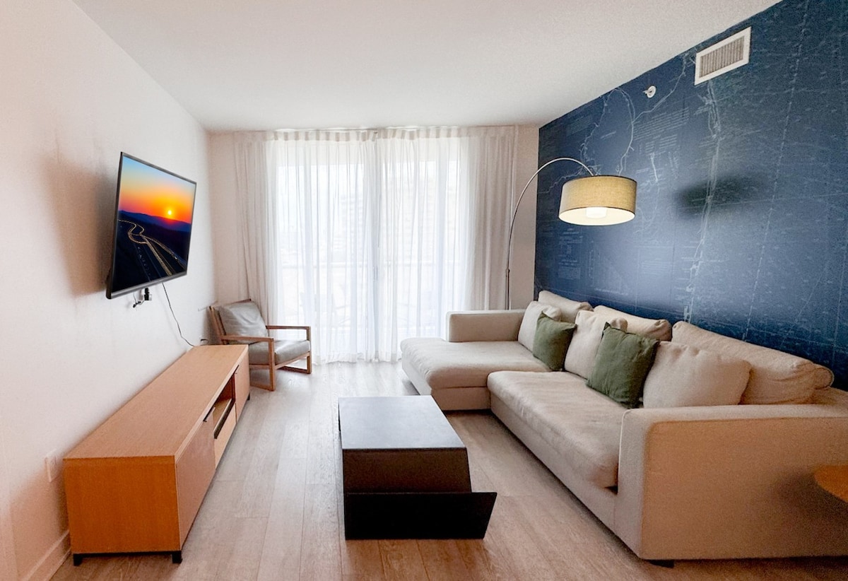 ห้องนั่งเล่นสว่างไสวพร้อมระเบียงและวิวเมือง