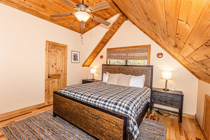 მყუდრო საძინებელი მთაში მდებარე ლოფტის ტიპის ხის სახლში, სადაც არის 183×224 სმ ზომის საწოლი და ხის თბილი მოპირკეთება.