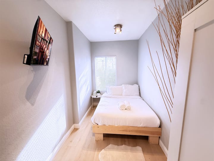 Bedroom #5 Downstairs featuring a Queen bed, smart TV, and dresser for easy settling in.