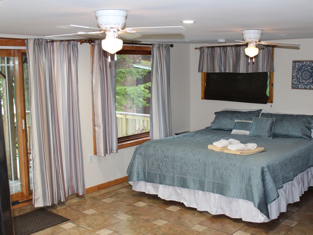 غرفة نوم تضم سرير كينج مع سطح يطل على البحيرة