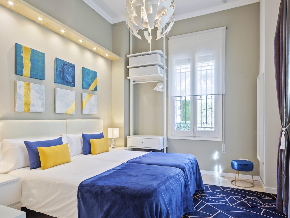 Bedroom 1: Located on the ground floor, this bedroom features an en suite bathroom and two beds that can be arranged as a double or as two singles upon request. It also includes a TV and a safe, with large windows providing excellent natural light.