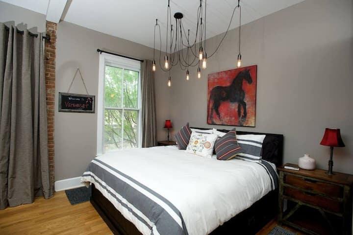 King-size bed with Casper mattress offers charging stations on the nightstands - blackout shades cover the historic original double hung windows overlooking Main Street