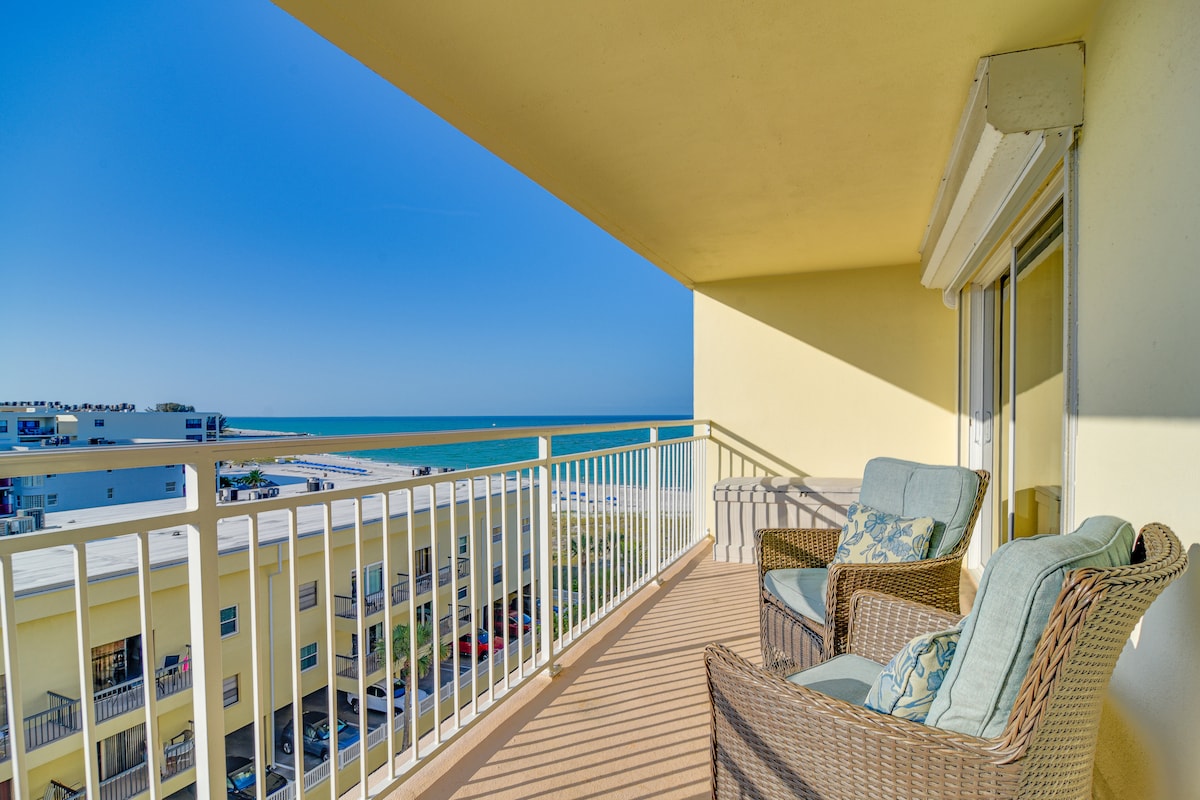 A covered balcony overlooks the sparkling Gulf waters, featuring two lounge chairs and a small table. The surrounding railing ensures safety while providing unobstructed views of the beach and ocean, inviting relaxation in the coastal atmosphere.