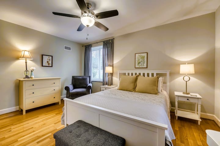 Dormitorio queen sereno con pisos de madera, sillón e iluminación suave