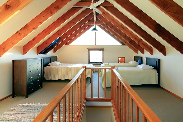 – Un encantador loft con una cama tamaño queen y dos camas individuales debajo de vigas de madera expuestas, ideal para familias o grupos.