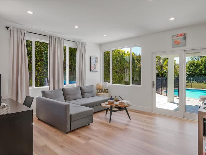 Cómodo sofá con Smart TV y una vista tranquila de la piscina y el patio trasero.