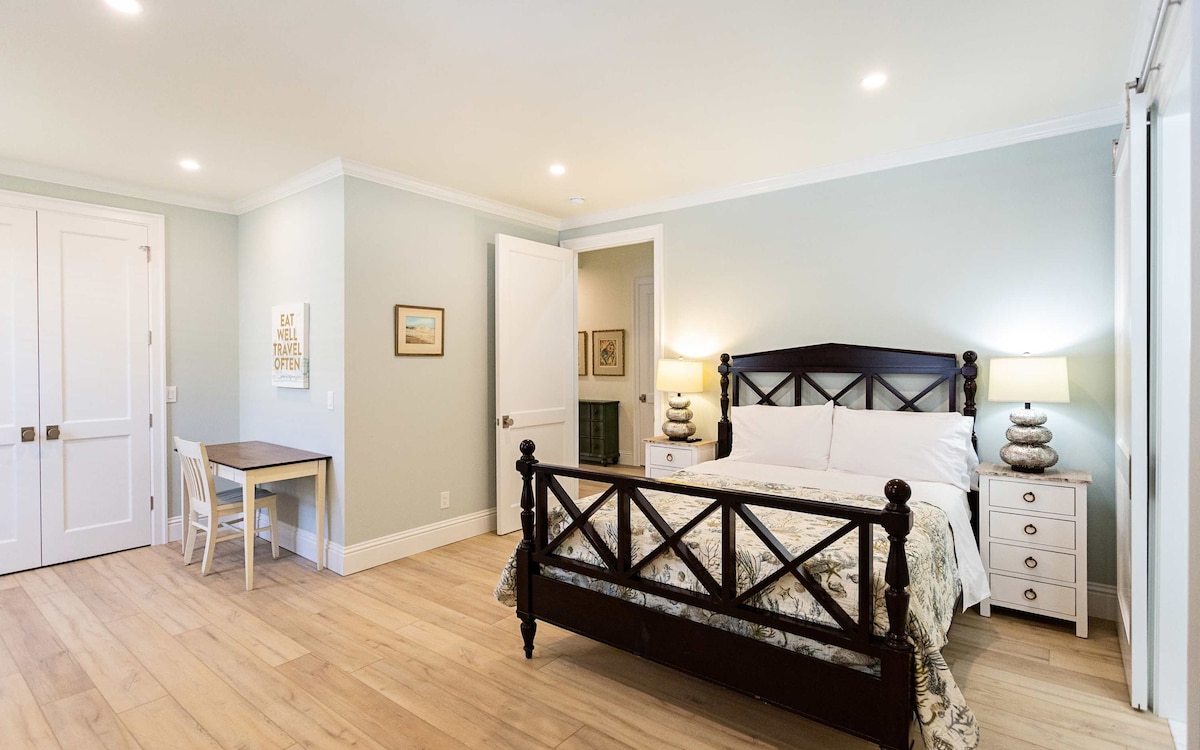 Dormitorio tamaño queen con cama tamaño queen, televisión, escritorio y baño adjunto.