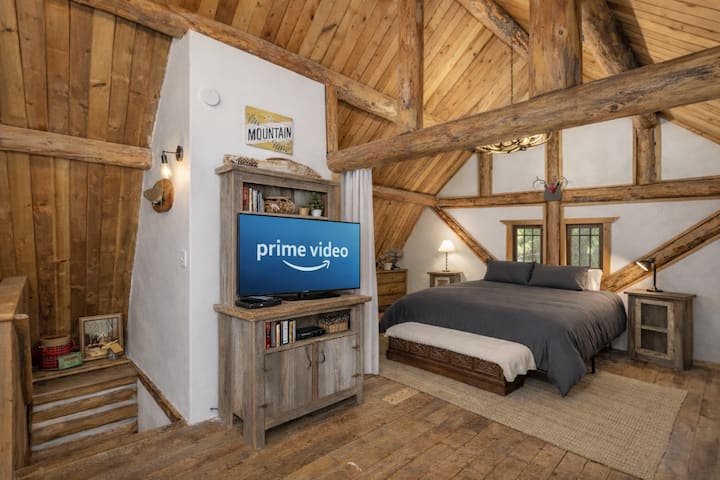 Gezellig in je rustieke loftslaapkamer met zichtbare houten balken, pluche beddengoed en een entertainmentcentrum voor perfecte avonden in de bergen.