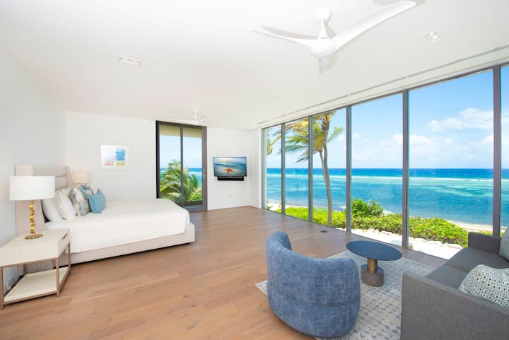 La suite principale de niveau supérieur avec un lit King Size, une télévision HD, un accès à deux terrasses, ainsi que des vues spectaculaires sur l'océan du sol au plafond. 