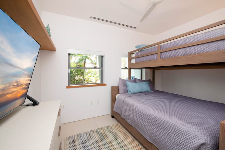 Chambre avec lits superposés au niveau inférieur avec lits jumeaux sur lits superposés complets.