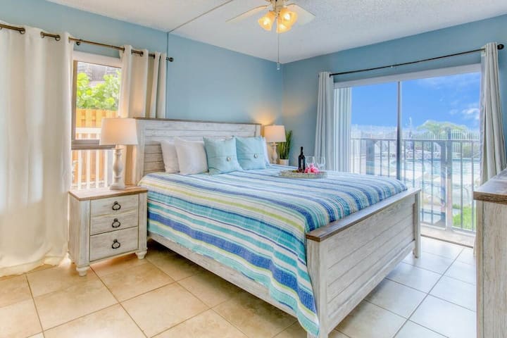 Acogedor y elegante dormitorio principal con cama tamaño king, TV y acceso al balcón para una estancia refrescante.
