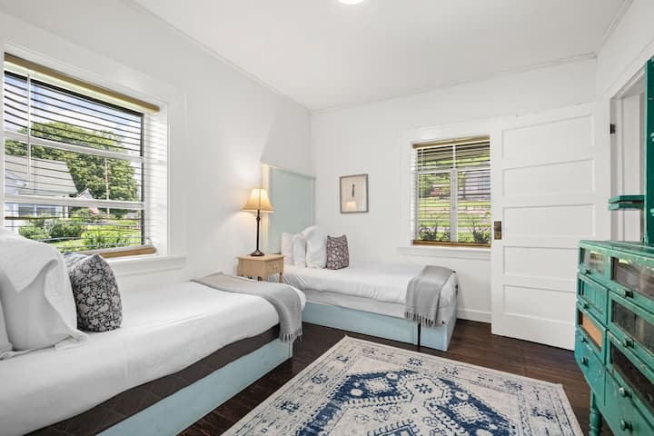 Bright light, soft bedding, and windows that frame the neighborhood charm—this room is all about comfort with a playful twist.