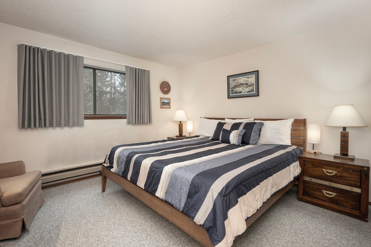 在舒适的卧室中，清爽的条纹床单和温暖的床头灯营造出完美的度假场所。