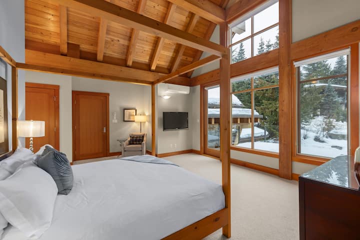 – Valaistu makuuhuone, jossa on holvattu puukatto ja metsänäkymät  
– Neljän pylvään sänky ja pehmeä valaistus luovat rauhallisen pakopaikan  
– Lämpimät sävyt ja luonnolliset tekstuurit korostavat vuorten rauhaa  