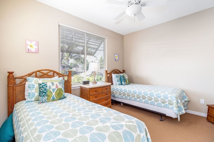 Dormitorio de invitados con dos cómodas camas individuales y una gran ventana.