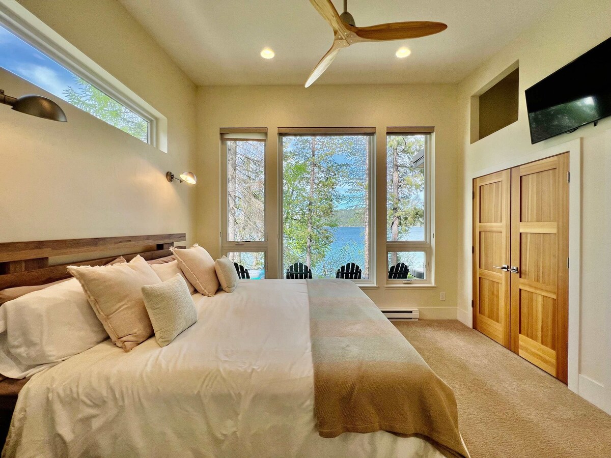 Dormitorio principal con cama tamaño king, televisión, vistas al lago y baño privado