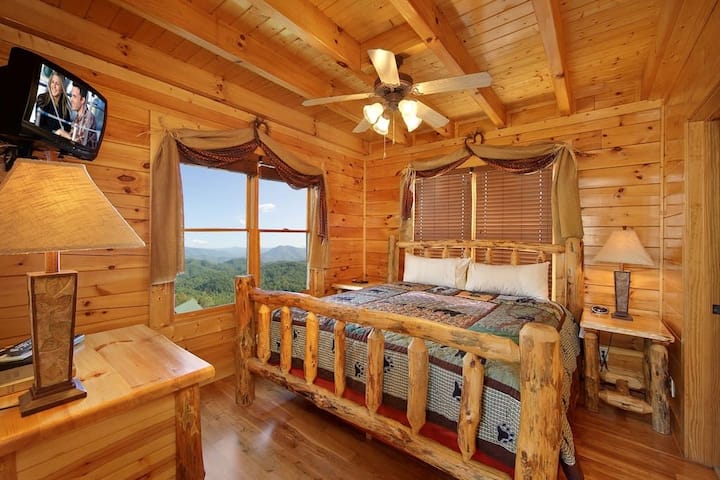 - Cozy bedroom with log furniture and stunning mountain view windows   - Plush bedding and wooden accents create a true cabin retreat   - Relax and recharge surrounded by warm Smoky Mountain style
