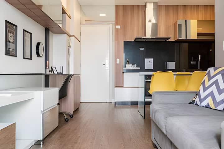 Kitchen integrated into the bedroom, with yellow chairs.