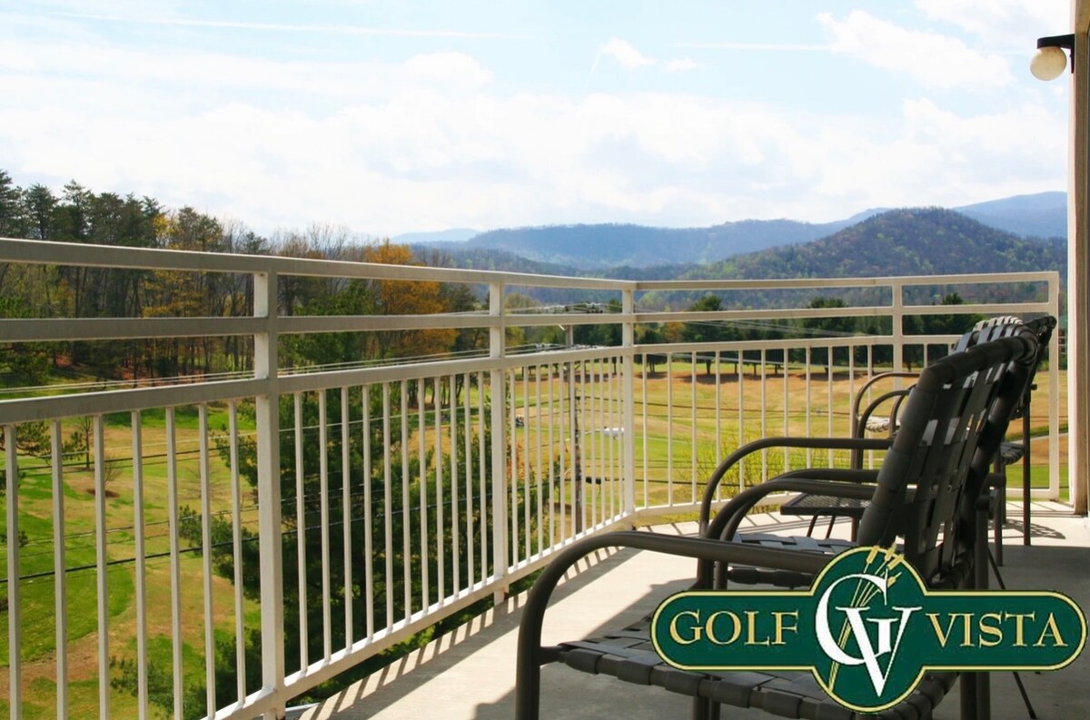 A private balcony features several comfortable chairs, offering unobstructed views of the surrounding mountains and golf course. The railing provides safety while allowing a clear perspective of the scenic landscape and the sky above.