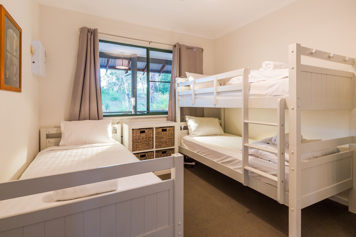 Оставете децата си да се насладят на скривалището си в третата спалня с двуетажно легло, единично легло и прозорец, показващ спокойния храст отвън.