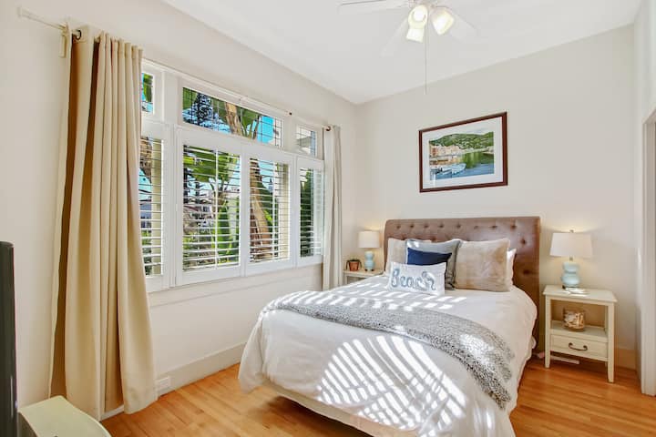Downstairs primary bedroom with queen bed offers shutters and drapes for peaceful sleeping and on-suite bathroom.