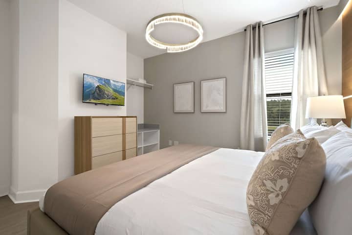 Lit king size moelleux, téléviseur mural et lustre chic. 