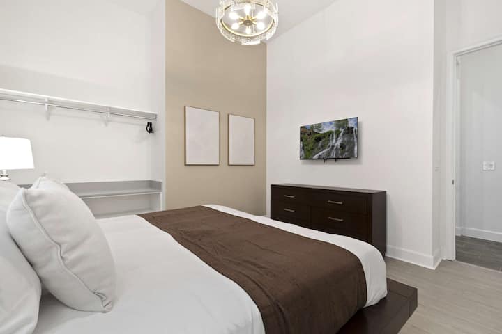 Hauts plafonds, lumière moderne et mur d'accent dans cette chambre élégante avec grand lit. 