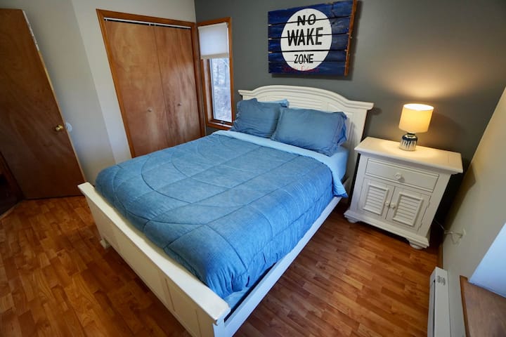 - Ingia kwenye usingizi mzito katika kitanda hiki chenye starehe kilichovaa mashuka ya bluu ya bahari
- Ishara ya "No Wake Zone" si ya kujifurahisha tu, ni mwaliko wako wa kupumzika
- Madirisha angavu, rangi nyeupe na mwanga wa starehe hufanya chumba hiki kionekane kama likizo ya kando ya ziwa