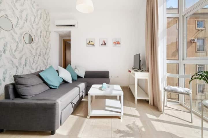 ห้องนั่งเล่นพร้อมเตียงโซฟาและหน้าต่างด้านนอก สมาร์ททีวีสว่างมาก ถนนเป็นถนนคนเดินไม่มีเสียงรบกวน 