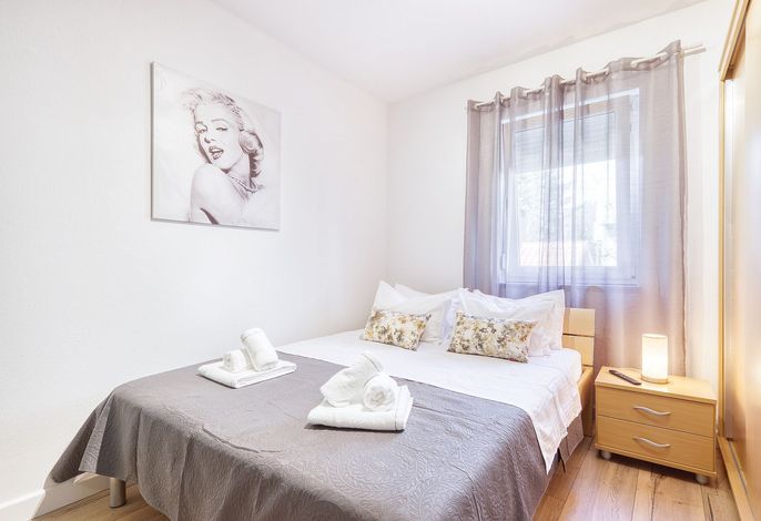 غرفة نوم أنيقة ومريحة مع إضاءة ناعمة، ولمسات من الأزهار، وديكور أنيق. مسكن مثالي للاسترخاء، يجمع بين الراحة ولمسة من الشخصية والسحر.