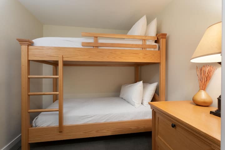 Dormitorio 2: habitación con literas ideal para familias o grupos con muebles de madera.  
- La ropa de cama cómoda y la iluminación cálida crean un espacio acogedor.  
- Habitación interior sin ventana diseñada para un descanso tranquilo.