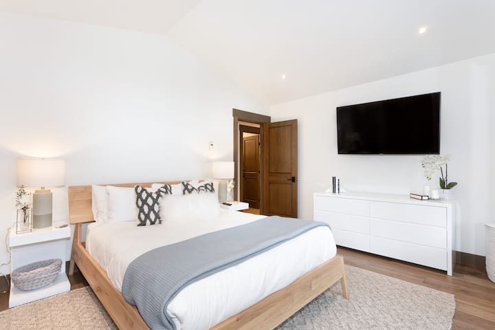 - Recámara 1: habitación luminosa con cama queen, diseño moderno y limpio y tonos neutros suaves 
- Las grandes ventanas y el acceso al balcón ofrecen relajantes vistas naturales a la montaña 
- La ropa de cama acogedora y las texturas cálidas crean un refugio tranquilo y cómodo