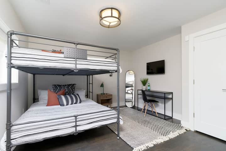 - Стилно двойно легло тип „Queen size“ с двуетажно легло, облечено в модерни раирани чаршафи - Включва елегантно бюро, телевизор, монтиран на стената, и високо огледало за комфорт и удобство - Монохромният килим и минималистичният декор създават лъскаво, уютно пространство за сън и работа