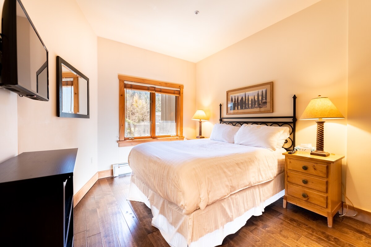 Spálňa pre hostí s manželskou posteľou a namontovaným televízorom s plochou obrazovkou. 