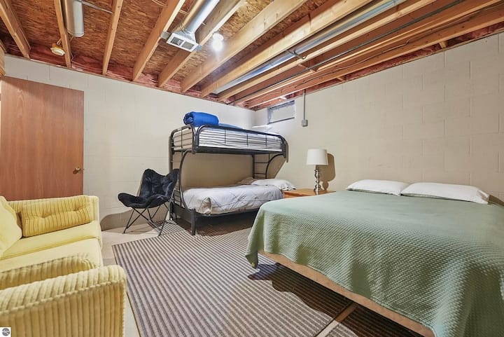 NIVEL INFERIOR: el área del sótano parcialmente terminada incluye una cama tamaño queen, literas individuales, sofá y vestidor.