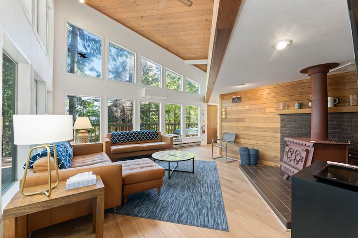 ห้องนั่งเล่นที่มีวิวทะเลสาบสองชั้นในตอนกลางวันที่น่าทึ่งผ่านต้นสนซีดาร์ที่โตเต็มที่ มีพื้นที่มากมายสำหรับการพักผ่อน เตาไม้ให้ความอบอุ่นเป็นพิเศษสำหรับช่วงเย็นที่หนาวเย็น!