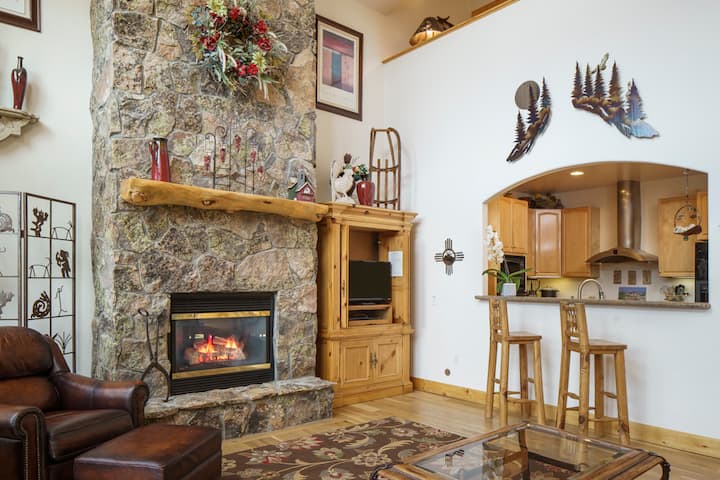 Mira hacia la chimenea, la televisión de pantalla plana y la cocina con barra de desayuno de 2 sillas.