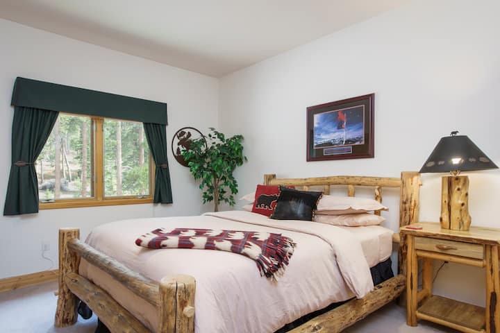 Vista del primer dormitorio con cama tamaño queen, cómoda de 4 cajones, pantalla plana y armario.
