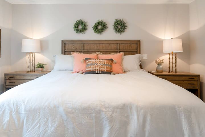 Master bedroom with king bed, plush new rug, full length mirror, sitting chair, and smart 50" TV with Netflix and Hulu Live subscriptions.