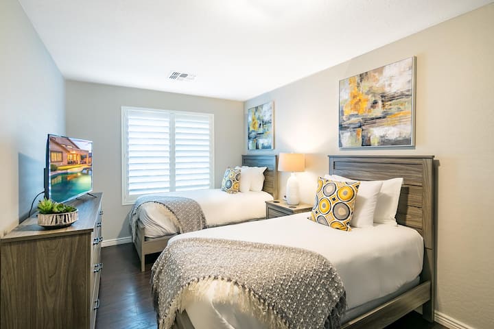 Пространа спална соба со високи тавани и приватен телевизор.