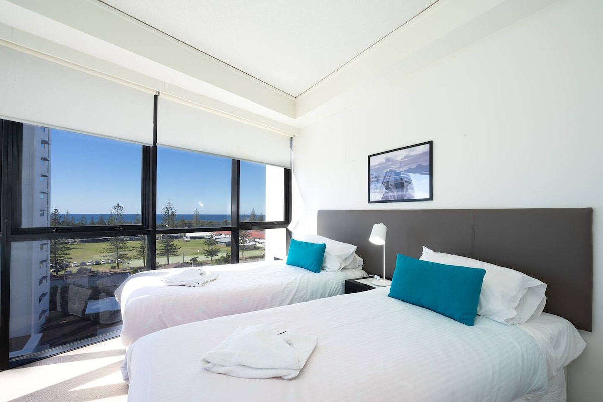 Събудете се с нежна гледка към океана в тази спокойна спалня с 2 отделни легла, където прозорците от пода до тавана и меката крайбрежна светлина поставят тона за спокойно начало на деня ви.