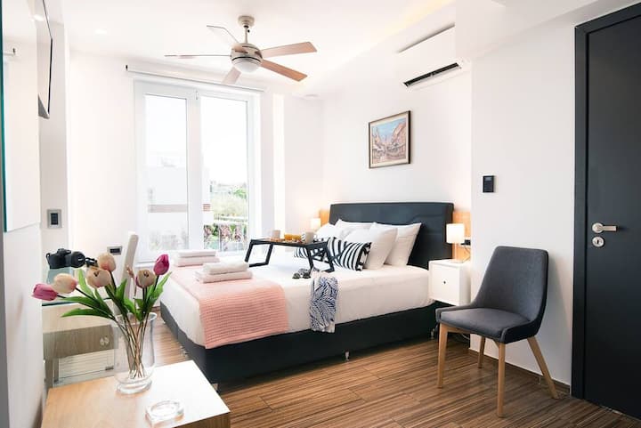 Φωτεινό υπνοδωμάτιο με διπλό κρεβάτι, ανεμιστήρα οροφής, άνετο καθιστικό και άμεση πρόσβαση στο μπαλκόνι.