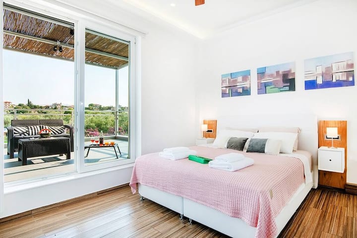 Φωτεινό υπνοδωμάτιο με διπλό κρεβάτι και άμεση πρόσβαση σε επιπλωμένο μπαλκόνι με θέα στην εξοχή.