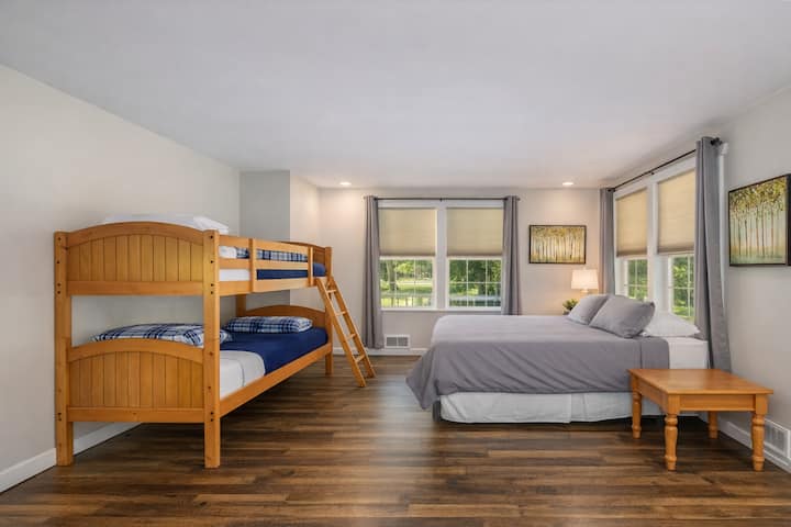 Descansa cómodamente en este espacioso dormitorio con cama tamaño queen y literas de madera, perfecto para familias con vistas panorámicas al jardín.