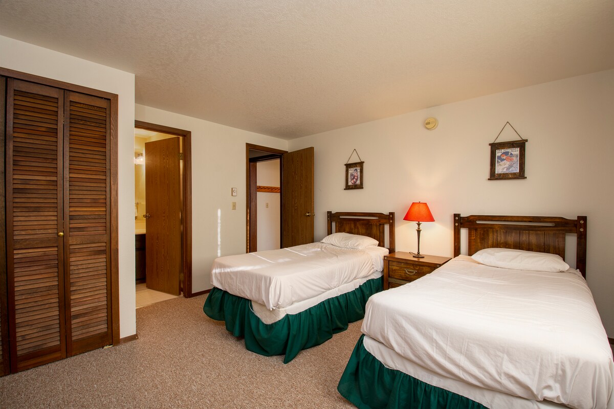 Dein gemütliches Schlafzimmer mit zwei Einzelbetten verfügt über bequeme Betten mit frischer Bettwäsche, warme Holzmöbel und durchdachte Details wie eine Beleuchtung am Bett.