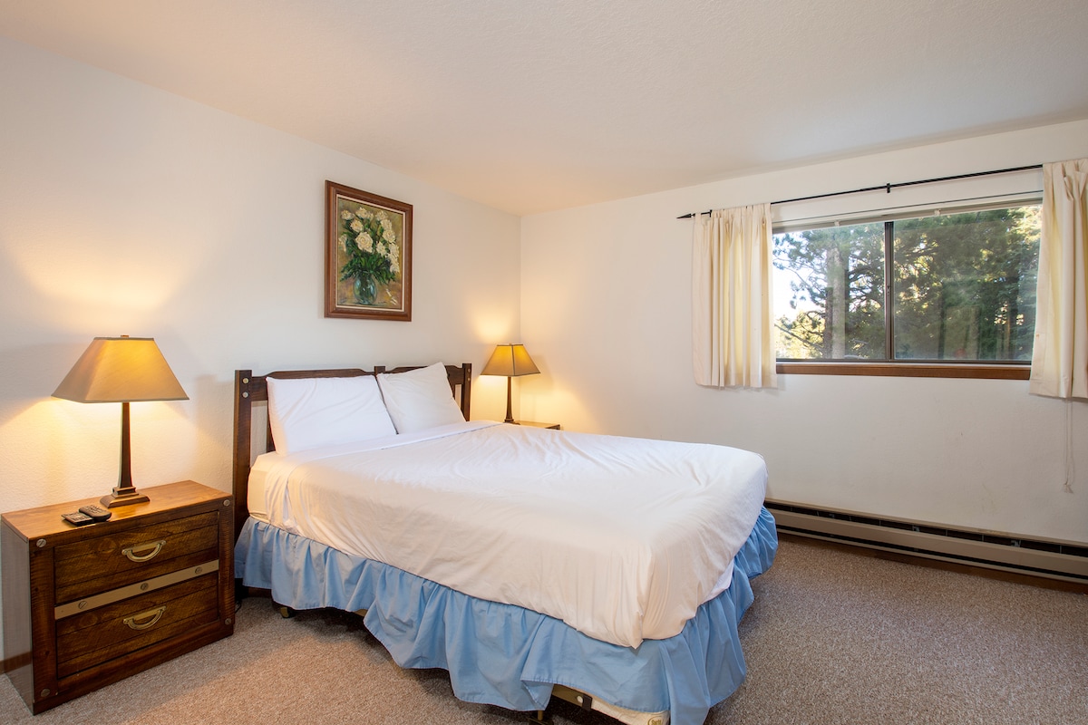 Mach es dir in deinem ruhigen Schlafzimmer mit frischer weißer Bettwäsche und warmer Beleuchtung am Bett gemütlich. Wache mit Waldblick durch dein Fenster auf.