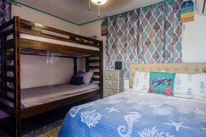 Second bedroom: queen + bunks, AC and fan, bright coastal charm