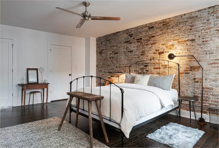 Bedroom #1 - A queen bedroom with an exposed brick wall, soft lighting, and vintage furnishings.